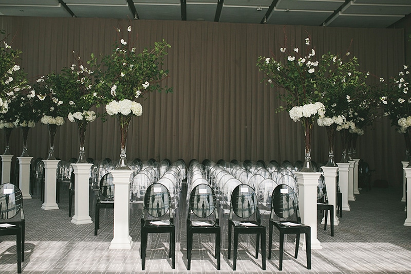 Black ghost chairs line the aisle at this modern black-tie wedding ceremony, as seen in Wedluxe. Planner: Rebecca Chan Weddings and Events www.rebeccachan.ca To see more, visit www.rebeccachan.ca